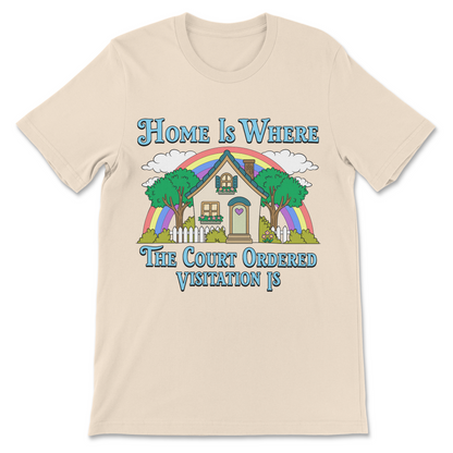 A light beige crewneck t-shirt featuring a colorful graphic of a house under a rainbow with the text 'Home Is WHERE The Court Ordered Visitation IS' in blue lettering.