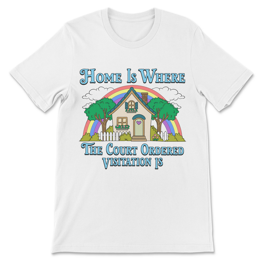 A white short-sleeve crewneck t-shirt with a colorful graphic print on the front. The graphic features a house, trees, a rainbow, and the text 'Home Is WHERE The Court Ordered Visitation IS' in blue lettering.