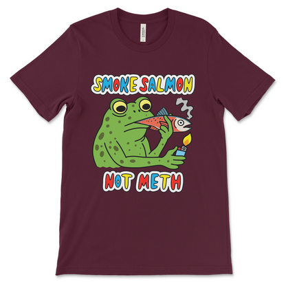 Absurd graphic tee with a frog smoking a whole salmon. Designed for lovers of dark humor t-shirts, cursed memes, and strange fashion statements.
